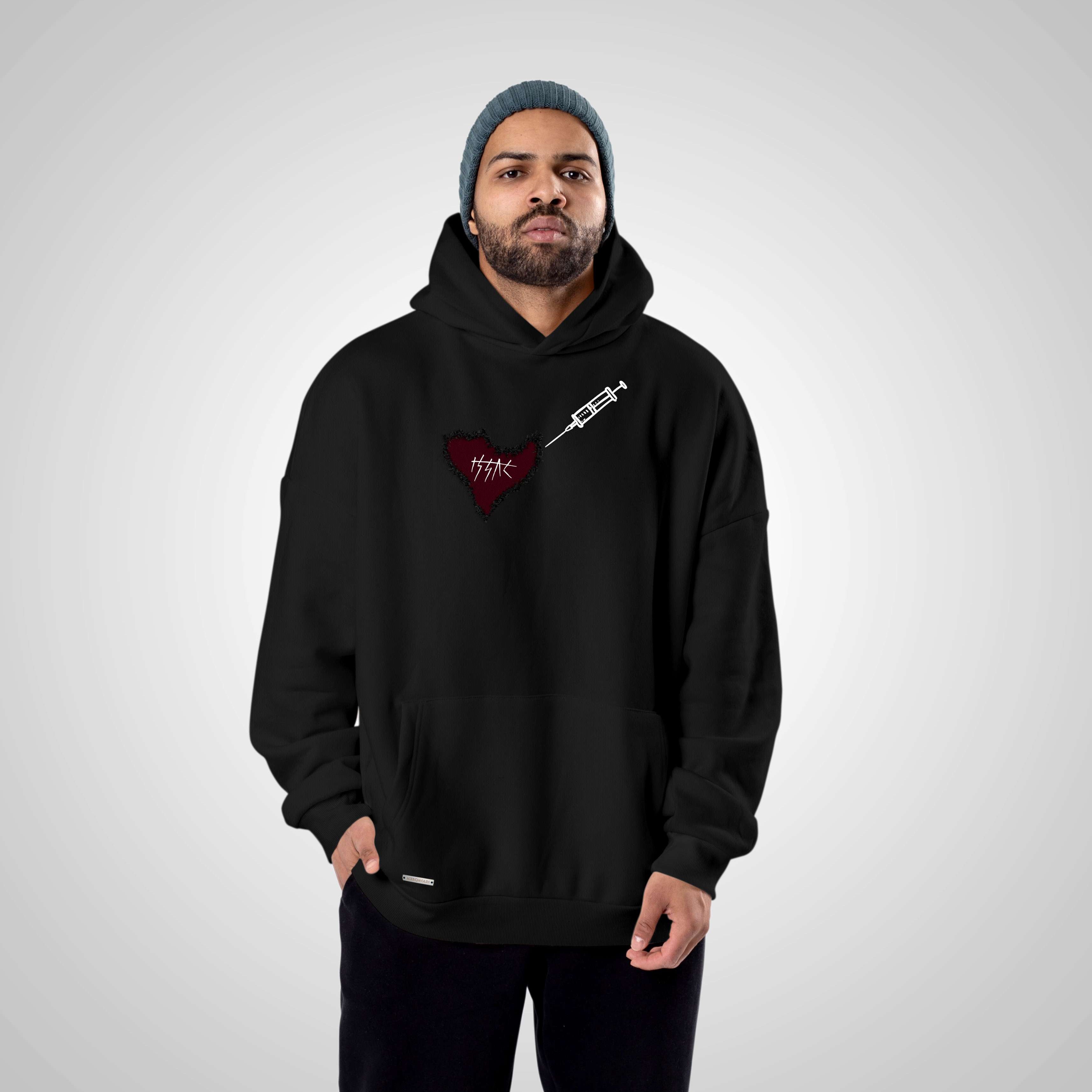 Man wearing a black hoodie with a red heart design on a gray background