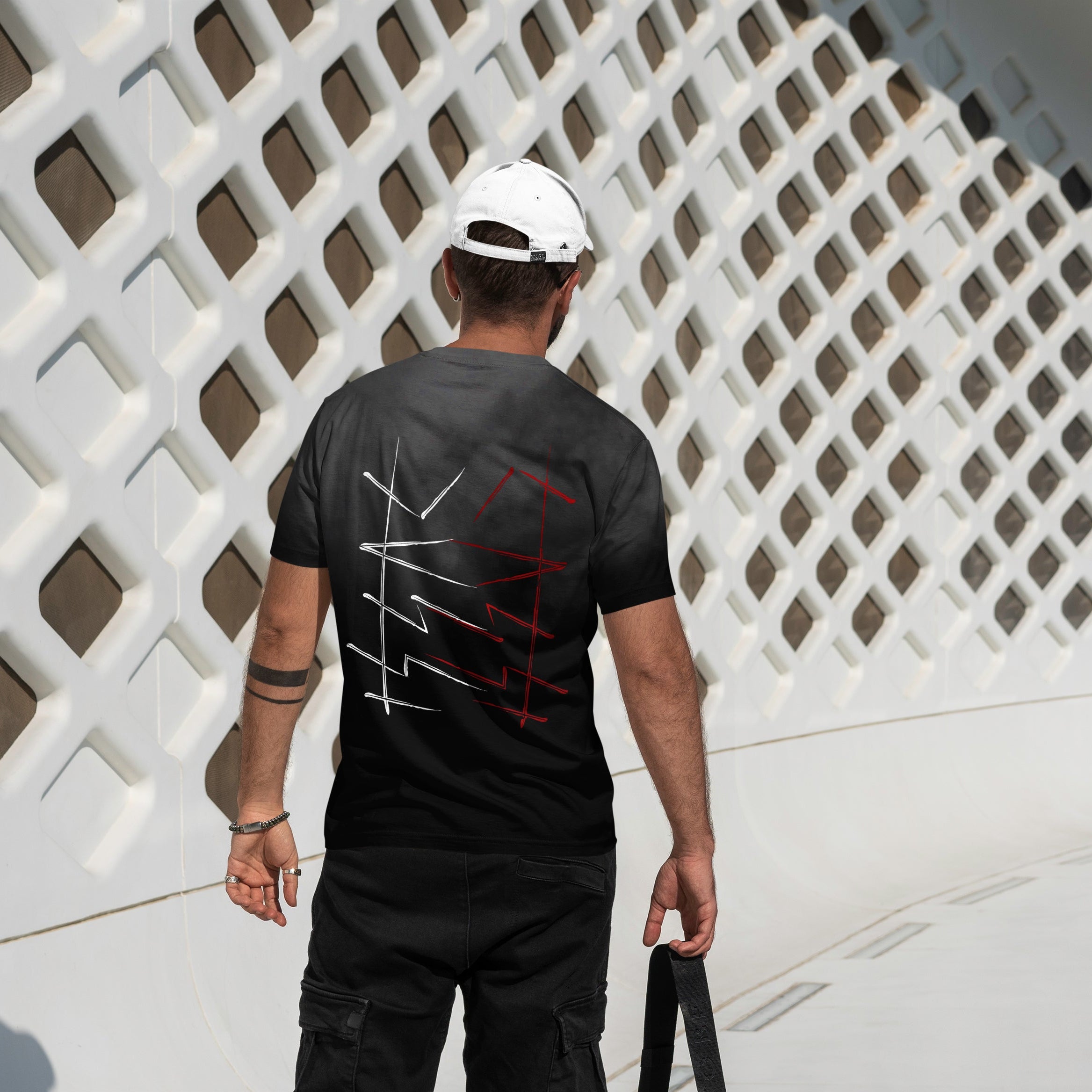 Person wearing a black t-shirt with a design, walking past a white lattice wall.