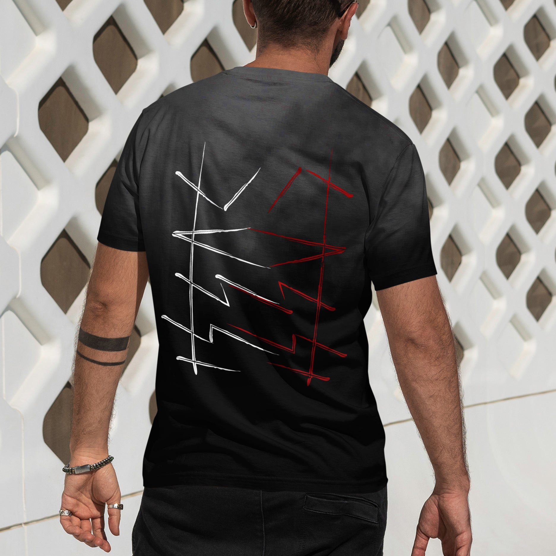 Person wearing a black t-shirt with red and white designs on the back, standing against a white lattice background.