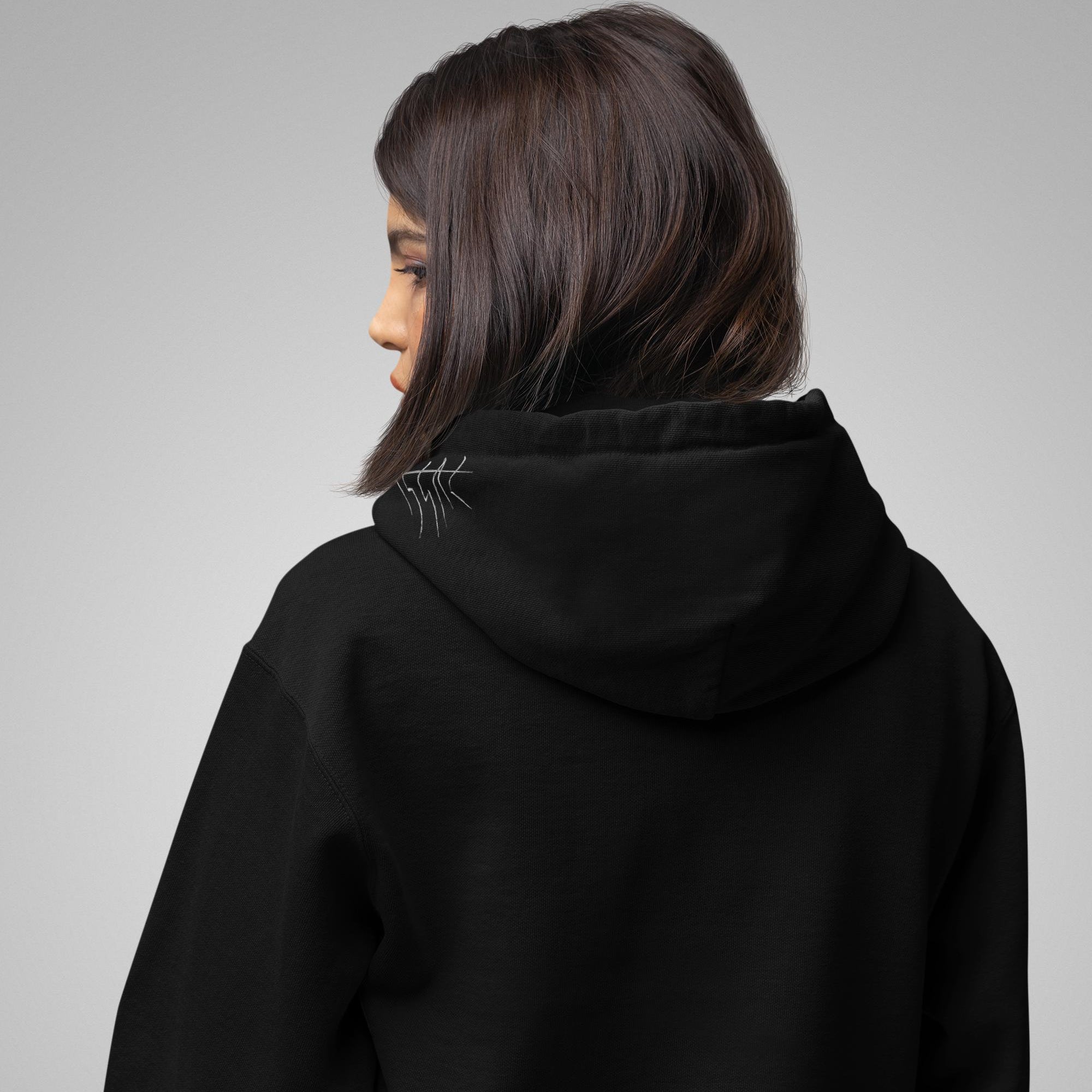 Person wearing a black hoodie from behind on a gray background