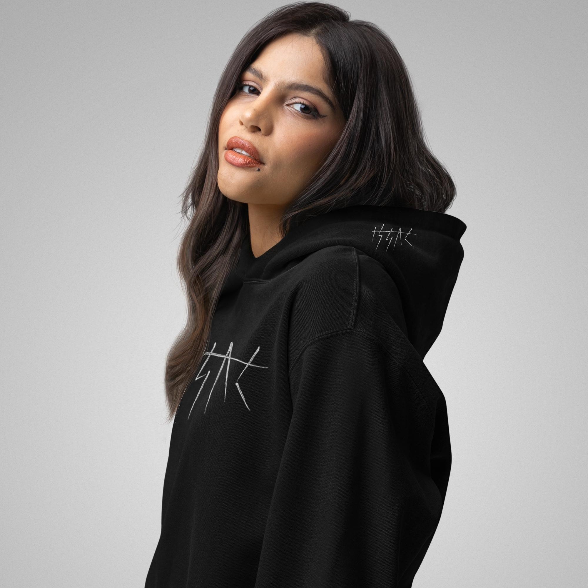 Woman wearing a black hoodie with a logo on a gray background