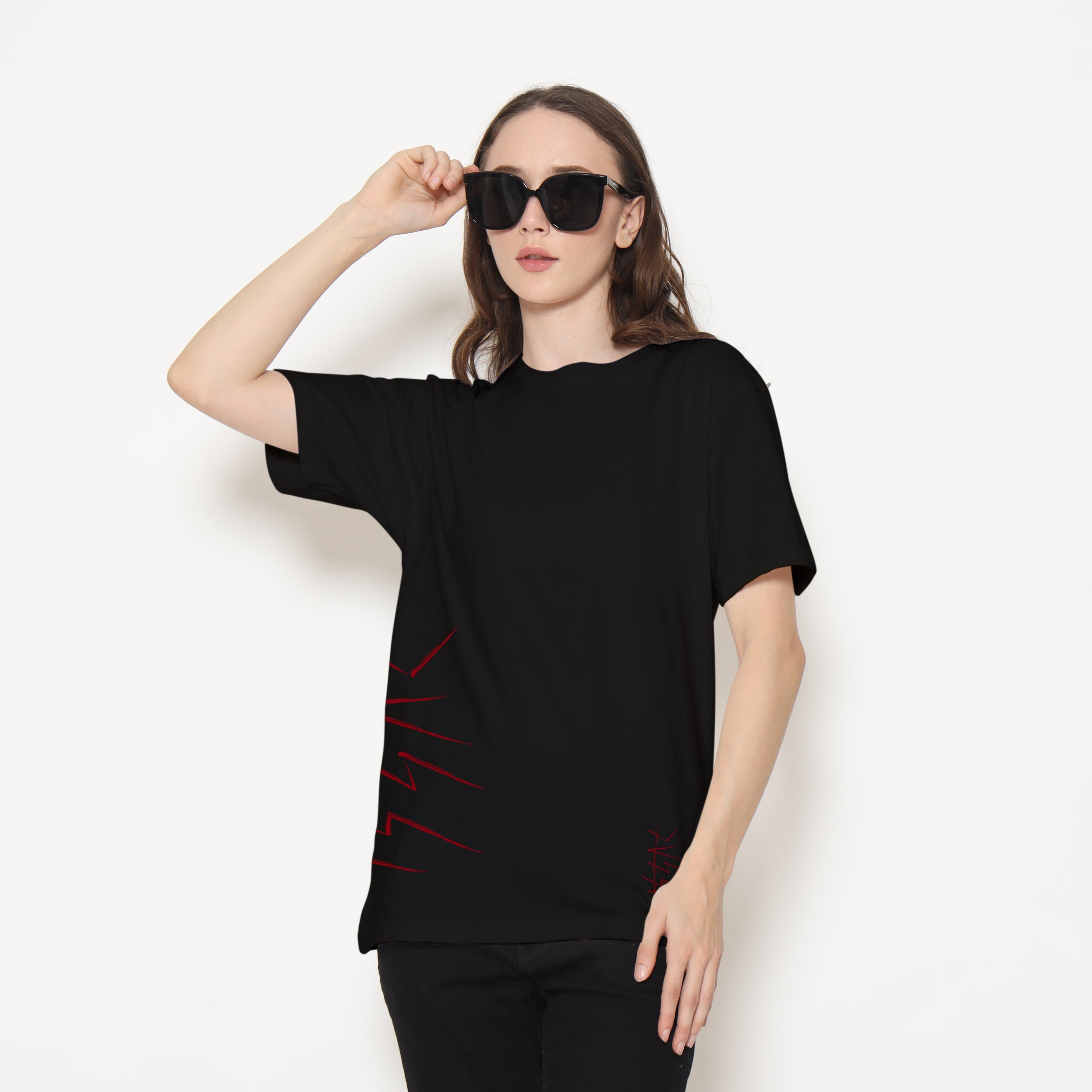 Woman wearing a black oversized top with red accents on a white background