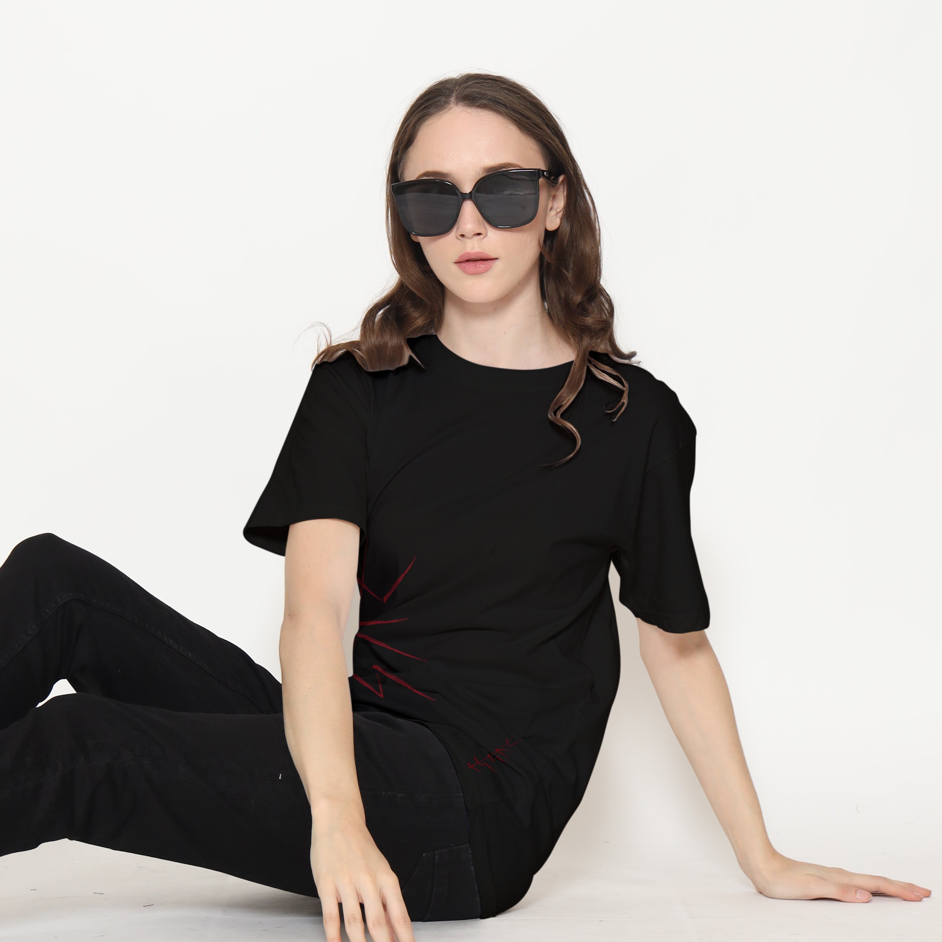 Woman wearing a black outfit and sunglasses on a white background